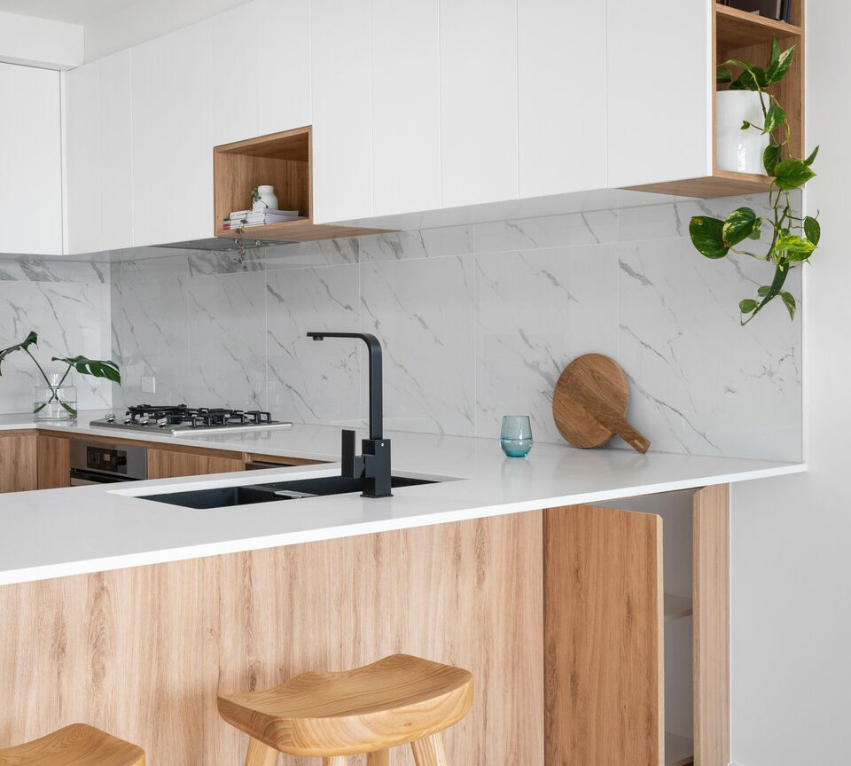 Helle Küche mit schwarzen Elementen, Wandfliesen aus Marmor und hellen Holzfassaden